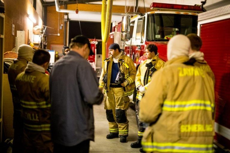 Group of firefighters standing in a building talking
