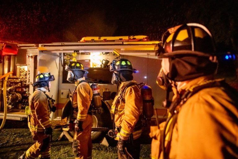 Firefighters at night standing near a fire truck