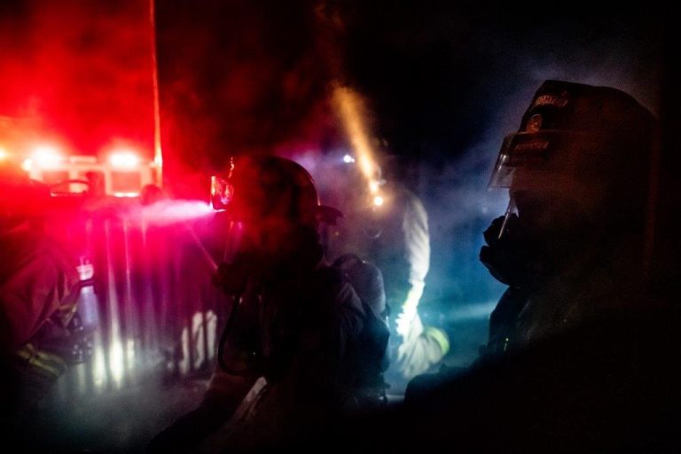 Firefighters at night in front of a fire truck